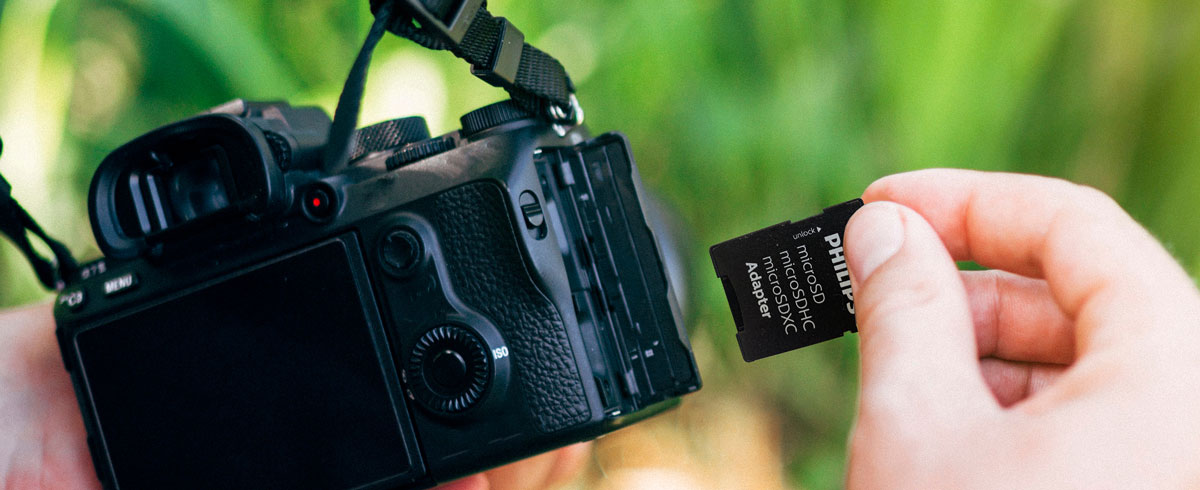 Personne tenant un appareil photo dans une main et une carte m&eacute;moire dans l'autre, pr&ecirc;te &agrave; capturer l'instant
