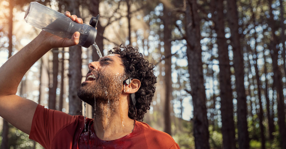 Un athl&egrave;te verse de l'eau sur des &eacute;couteurs &eacute;tanches &agrave; oreille ouverte