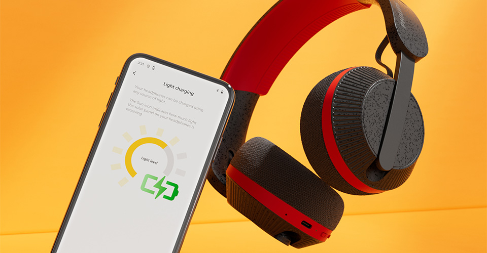 Casque Philips A6219 &agrave; c&ocirc;t&eacute; d'un smartphone affichant l'&eacute;cran de chargement lumineux, sur un fond orange vif