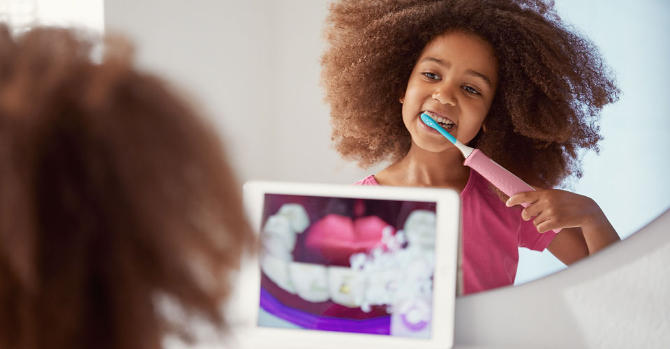 Een jong meisje poetst haar tanden met de Philips Sonicare For Kids en gebruikt de app voor de goede poetstechniek.