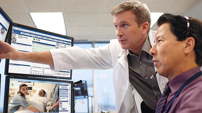 Un clinicien et un expert surveillent le programme de telesante hospitalier sur ecrans