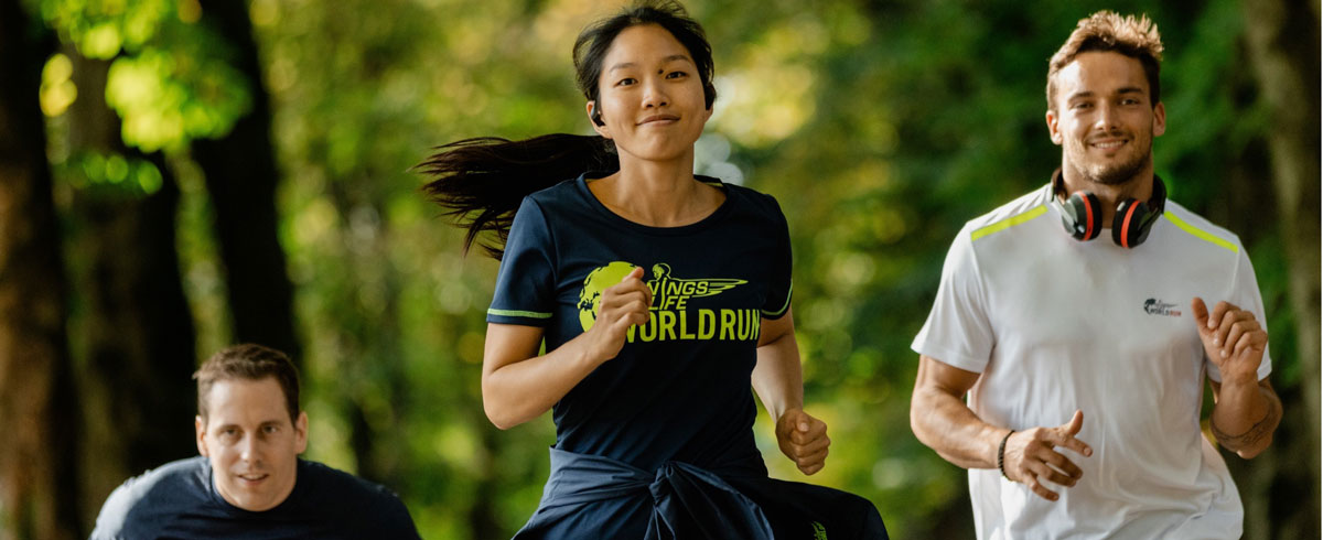 Drie Wings for Life World Run-deelnemers zijn opgetogen aan het hardlopen en dragen Philips-sportkoptelefoons.
