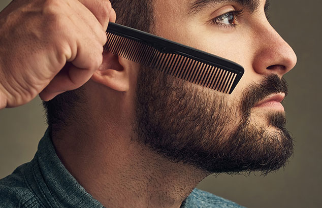 Zijprofiel van een man met een volle baard die zijn gezichtsharen op hun plaats laat kammen.